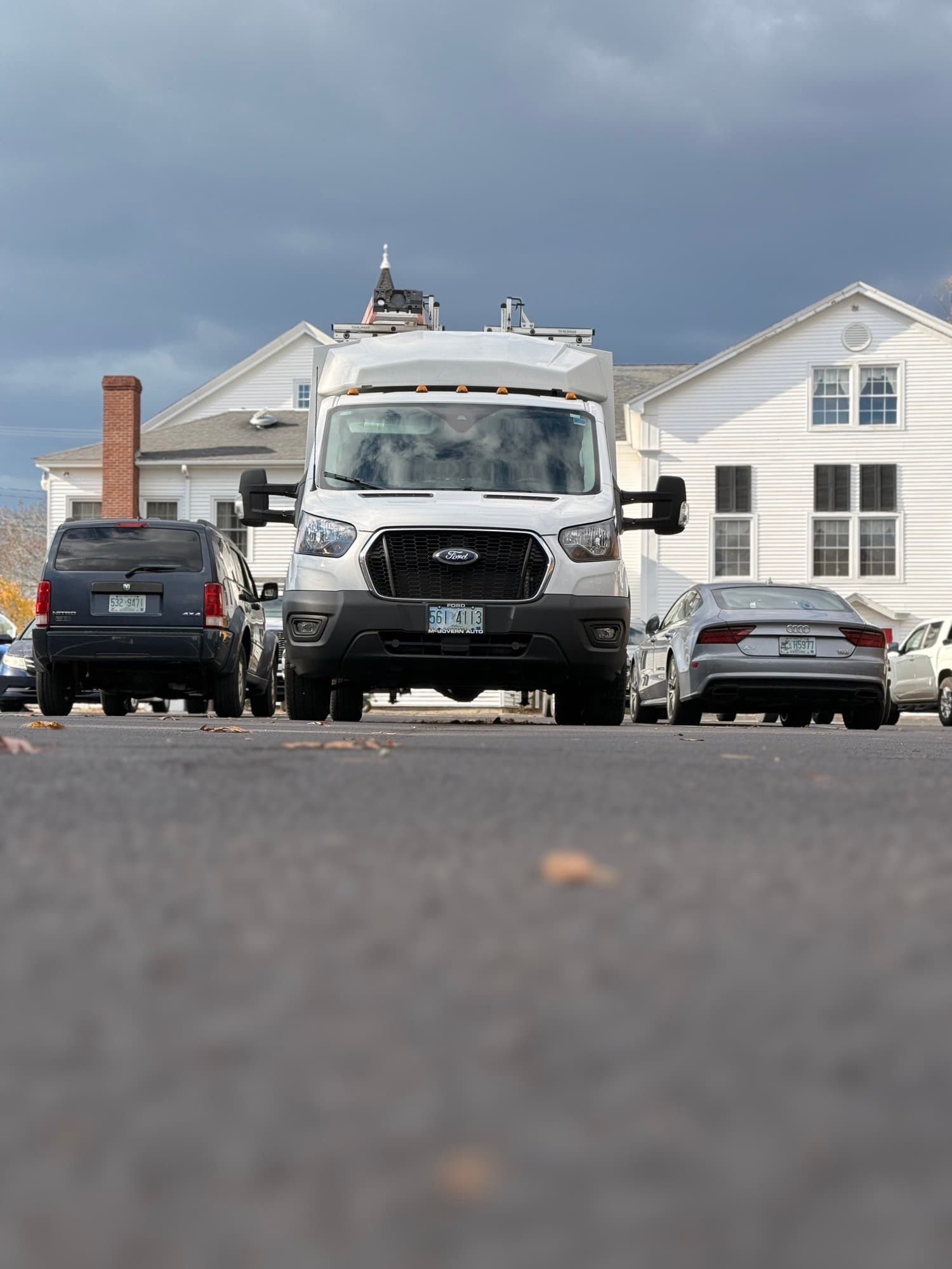 Head-on view of the Barrasso Electric van parked outside a white clapboard building