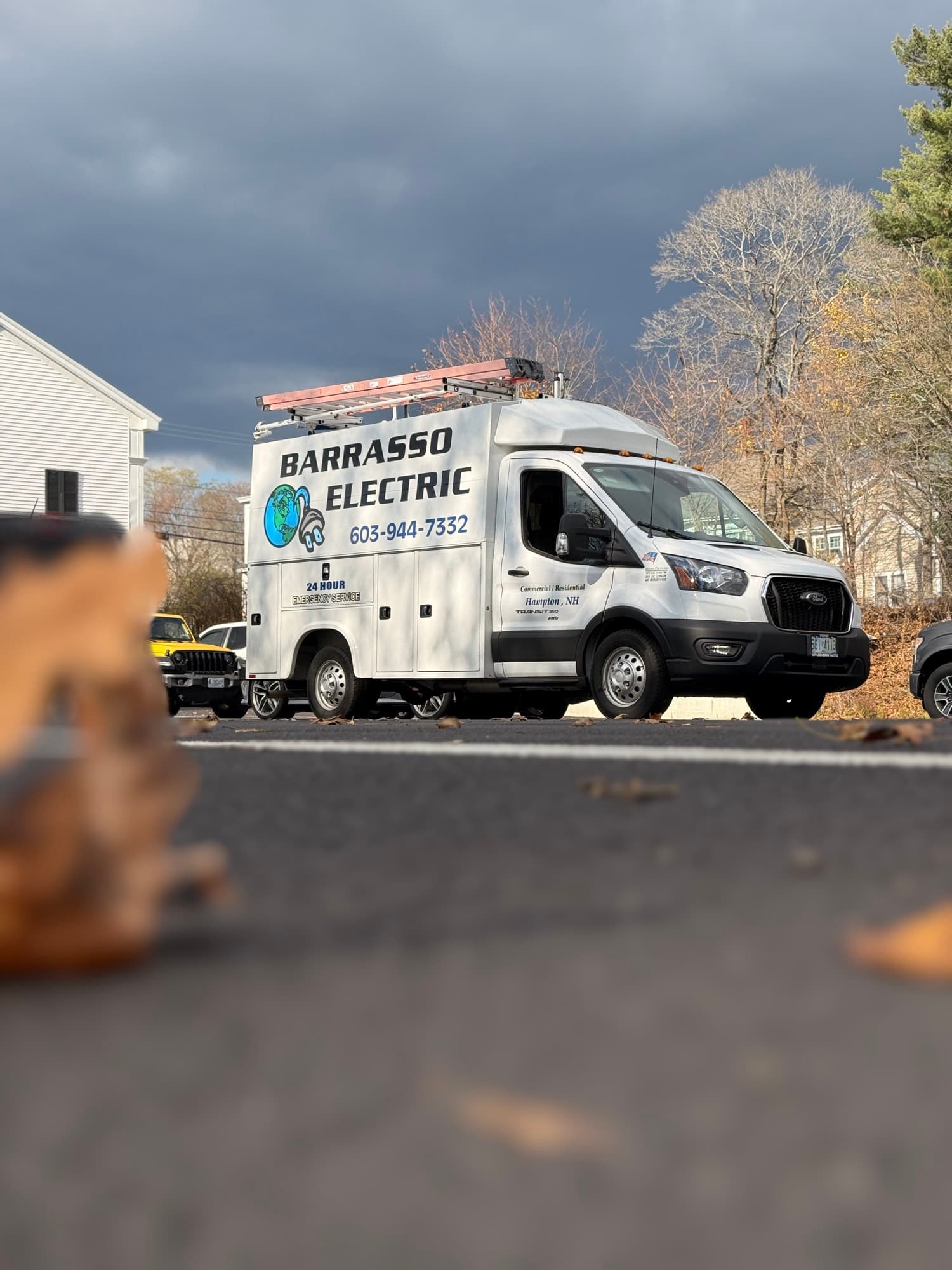 Low view across the lot of the Barrasso Electric van beneath a storm sky