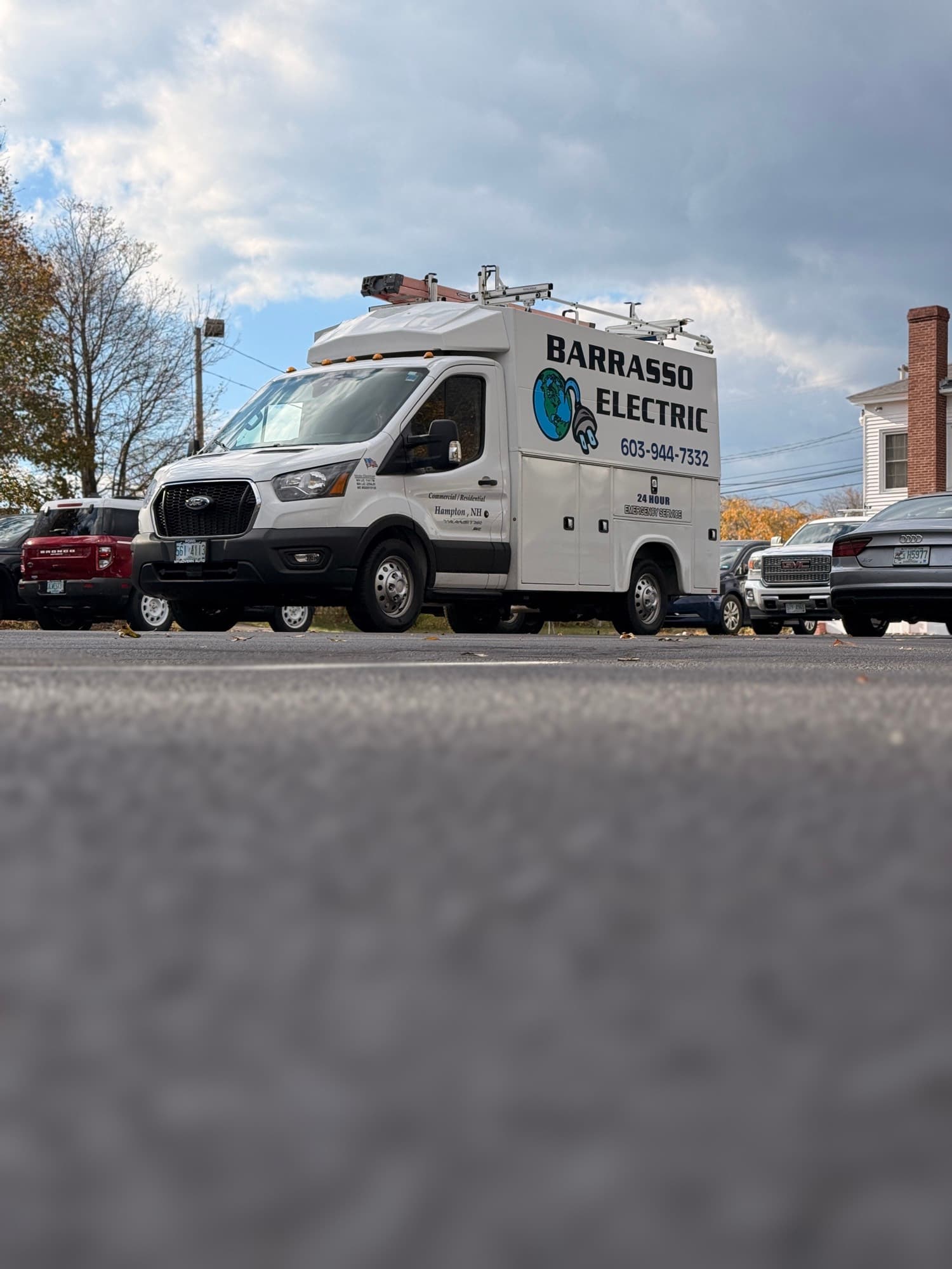 The Barrasso Electric van parked among cars on an autumn afternoon